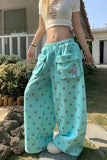 Person wearing light blue pants with polka dots and a white top outdoors.