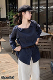 Woman wearing a blue pinstripe shirt and white pants in an outdoor setting.