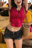 Person wearing a red top and black shorts with a straw bag, standing in a casual indoor setting.