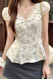 Woman wearing a floral blouse with a starfish necklace, standing outdoors.