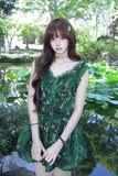 Woman in a green dress standing in a garden with pond and trees