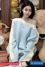 Woman wearing a light blue sweater with a white border, sitting among stuffed animals.