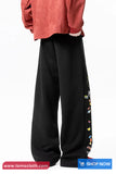 Black wide-leg pants with colorful side stripe worn by a person, with 'Toms Cloth' branding.