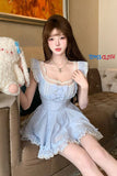Person wearing a light blue dress holding a plush toy in a room with a couch and painting.
