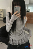 Person wearing a gray long-sleeve top with a ruffled skirt in a room.
