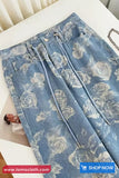 Blue jeans with floral pattern on a white surface, brand 'TomsCloth' visible.