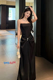 Woman in a black strapless gown standing in a modern interior setting with 'TOMS CLOTH' branding.