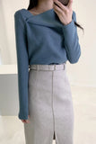 Person wearing a blue sweater and gray skirt against a neutral background