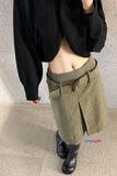 Person wearing a black sweater and green skirt with a plain background