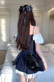 Person wearing a polka dot dress with a large bow in a room.