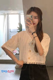 Woman taking a mirror selfie wearing a white blouse with lace details.