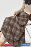 Person wearing a plaid skirt with a neutral background and 'tomscloth.com' branding.