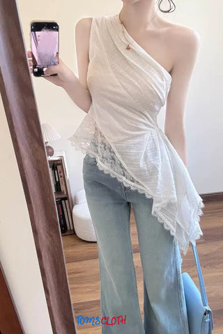Person wearing a white lace top and light blue jeans taking a mirror selfie.