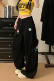 Person wearing black pants with colorful flower patches in a room.