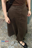 Person wearing a brown skirt on a stone pavement with 'TOMS CLOTH' branding.