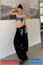 Person wearing a blue top and black pants in front of a LILIPOP branded wall.