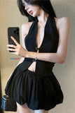 Woman wearing a black halter top and shorts, taking a mirror selfie.