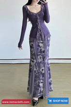Woman wearing a long purple dress with floral patterns on a plain background