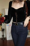 Person wearing a black velvet top and blue jeans with a blurred background