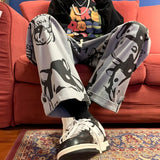Person wearing gray pants with black designs sitting on a red couch.