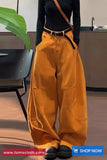 Person wearing mustard yellow pants with a black top and shoes in an indoor setting.