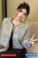 Woman wearing a gray textured jacket with a visible brand logo in the corner.