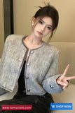 Woman wearing a gray textured jacket with a visible brand logo in the corner.