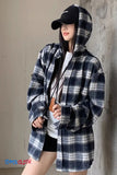 Person wearing a plaid coat and black cap against a plain background