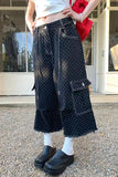 Person wearing black polka dot pants with a white top and red jacket outdoors.