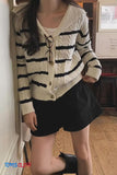 Person wearing a striped cardigan and black shorts indoors