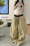 Person wearing beige wide-leg pants and a white top in a room with a TV and desk.