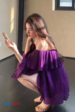 Woman in a purple off-shoulder dress sitting on the floor.