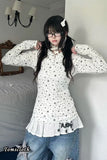 Person wearing a white floral blouse and blue jeans in a room.