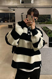 Person wearing a black and white striped sweater taking a mirror selfie.