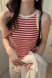 Person wearing a red and white striped tank top holding a white towel.
