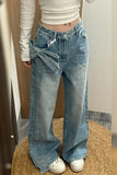 Person wearing blue jeans with a bow tie, standing on a woven mat.