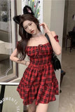 Woman in a red and black checkered dress with cat ears posing indoors.