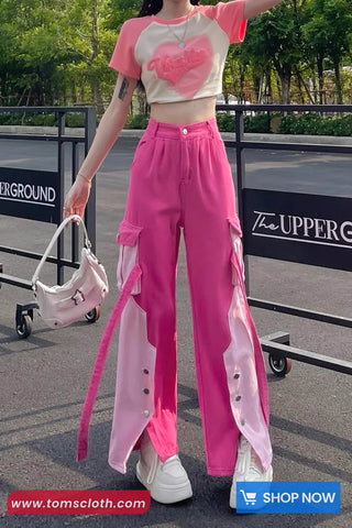 Person wearing a pink outfit with a white shirt, standing outdoors with a blurred background.