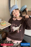 Child wearing a brown sweater with a cat design, blue beret, and plaid skirt, holding a donut.