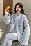 Woman wearing a light blue textured coat with colorful buttons, holding a piece of fruit.