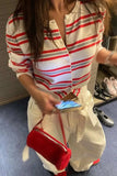 Person wearing a red and white striped shirt with a red bag, standing indoors.