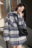 Woman wearing a patterned coat with a black handbag, standing outdoors.