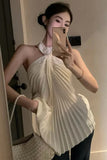 Woman taking a mirror selfie wearing a white halter top with floral details.