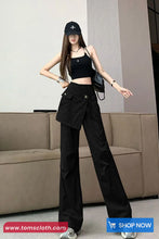 Woman wearing a black outfit with wide-leg pants and a cap in an indoor setting.