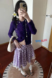 Person wearing a purple top and polka dot skirt, holding a beige handbag, with 'TOMS CLOTH' branding.