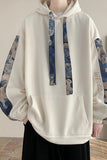 White hoodie with blue and brown patterned sleeves on a plain background