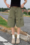 Person wearing green cargo shorts on a road with grass and buildings in the background