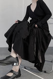 Person wearing a black outfit sitting on a chair with a plain background