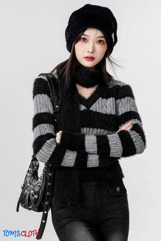Person wearing a black and gray striped sweater with a black beanie and bag on a white background