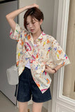 Woman wearing a colorful patterned shirt and dark shorts indoors.